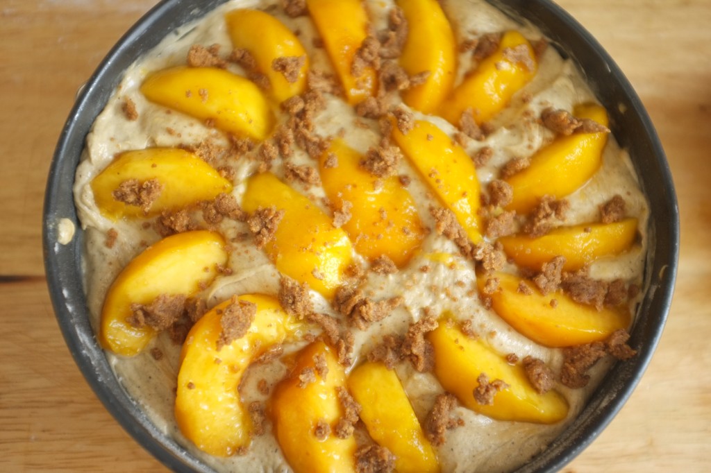 Le gâteau avant cuisson vu de dessus, pêches et crumble de sucre à la cannelle