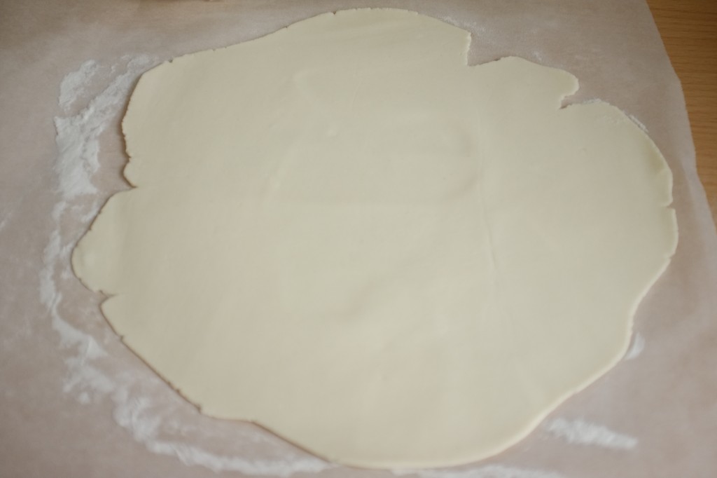 La pâte feuilletée sans gluten est étalée entre deux feuilles de papier cuisson, saupoudrées elles, de farine de riz