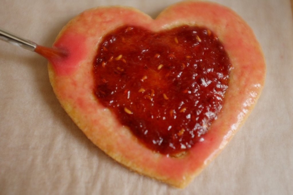 Le glaçage coloré à la framboise est déposé sur les bords du biscuit à l'aide d'un pinceau