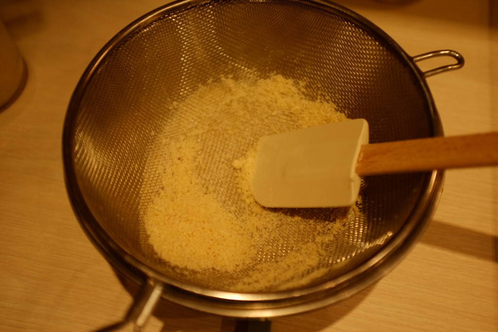 La poudre d'amande et le sucre glace est tamisé à travers un passoire.