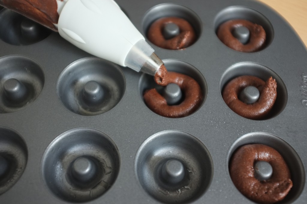 la pâte sans gluten au chocolat est déposé dans les cavités du moule à mini donuts