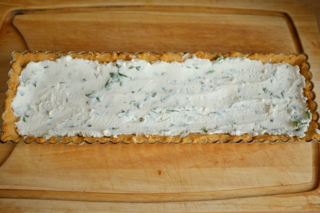 Le fond de tarte sans gluten est recouvert du mélange de fromage de chèvre frais et basilique