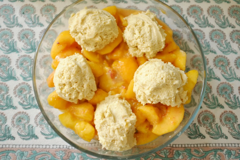 je dépose la pâte sans gluten en 5 boules sur les pèches. Le cobbler à la pèche avant d'être enfourné