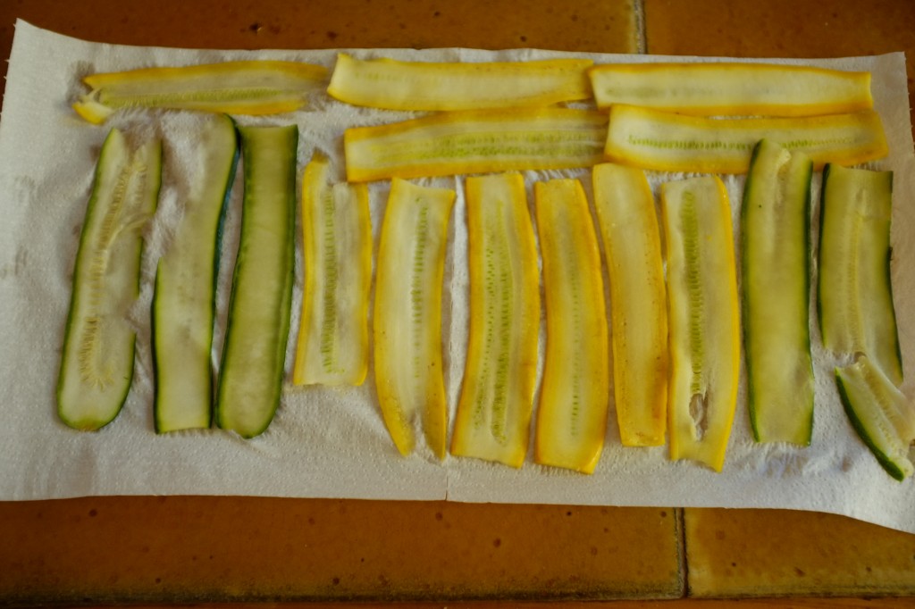 Les lamelles de courgettes sont déposées sur du papier absorbant pour éponger l'eau