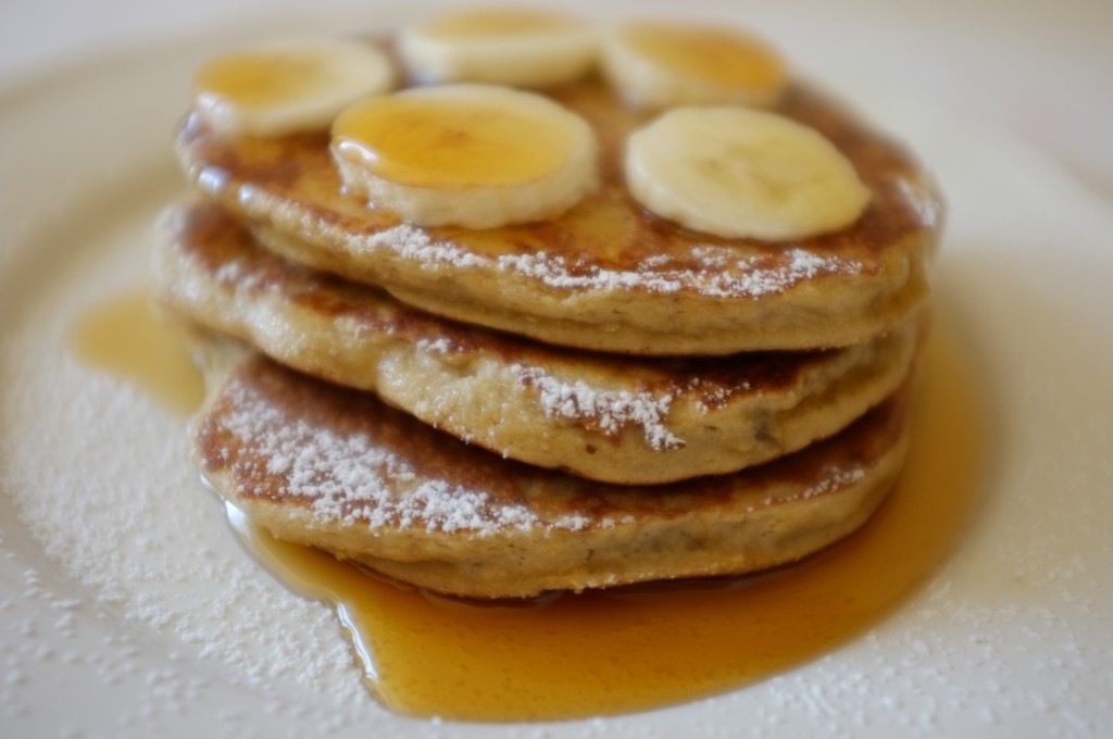 Les pancakes sans gluten noix de coco-banane, servies avec des rondelles de banane fraiches et du sirop d'érable