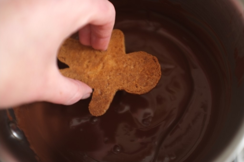 La face du biscuit Rudolphe est plongée dans le chocolat fondu