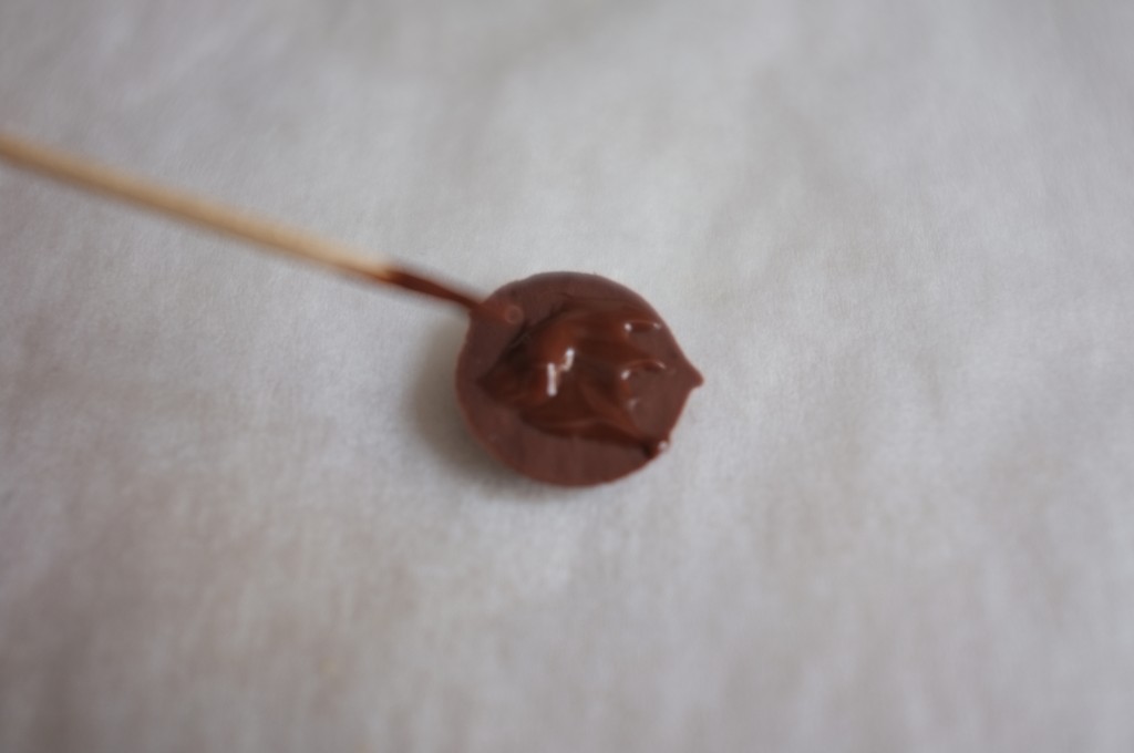 Pour coller les pastilles de chocolat qui vont former les nez, j'utilise un peu de chocolat fondu que j'applique à l'aide d'un pic en bois