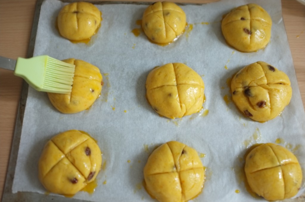 Chaque petits pains sans gluten est badigeonnés de glaçage à l'oeuf et sucre avant d'être enfournés.