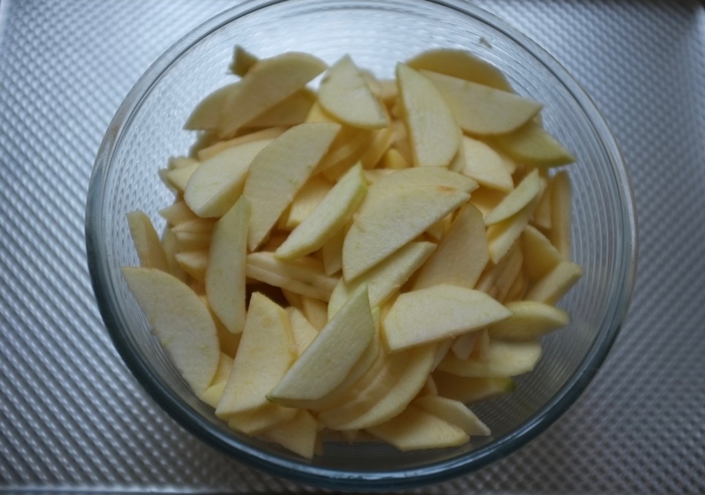 les fines lamelles de pommes dans le saladier sont arrosés de jus de citron frais