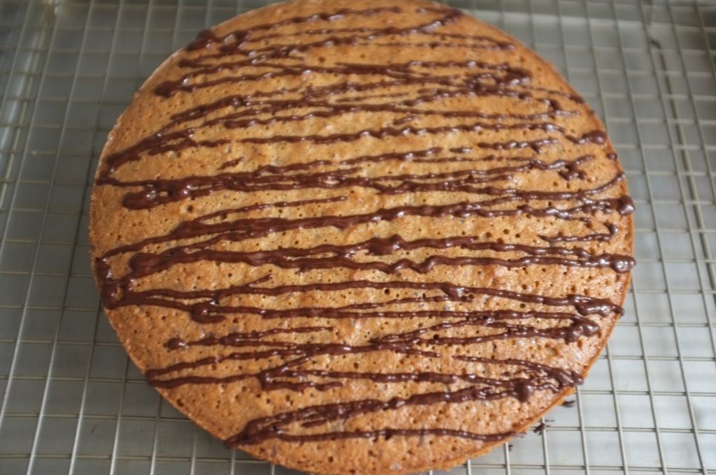 Le gâteau sans gluten châtaigne, coco et chocolat est décoré de chocolat noir fondu avec une cuillère d'huile de coco pour apporter une belle brillance.