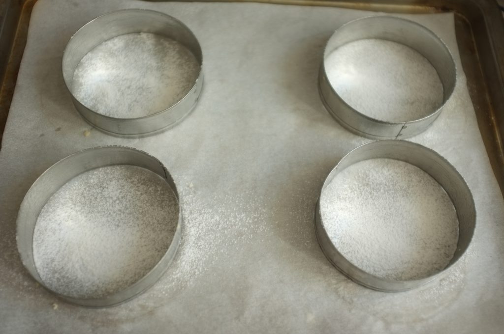 Les anneaux sont posés sur une feuille de papier cuisson, et l'intérieur est légèrement fariné.