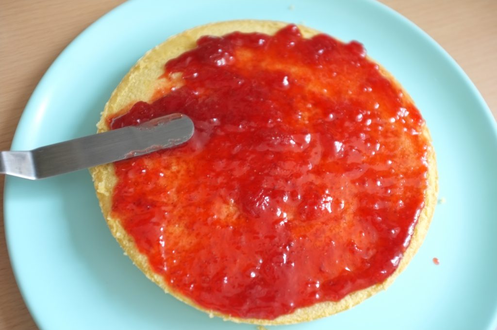 La première génoise sans gluten est recouverte de confiture de fraise.