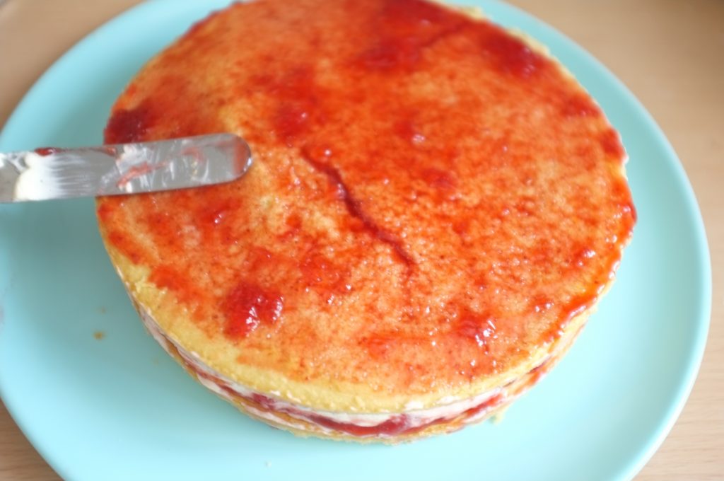 La seconde génoise sans gluten est recouvert d'une fine couche de confiture de fraise pour permetre à la pâte à sucre de coller.